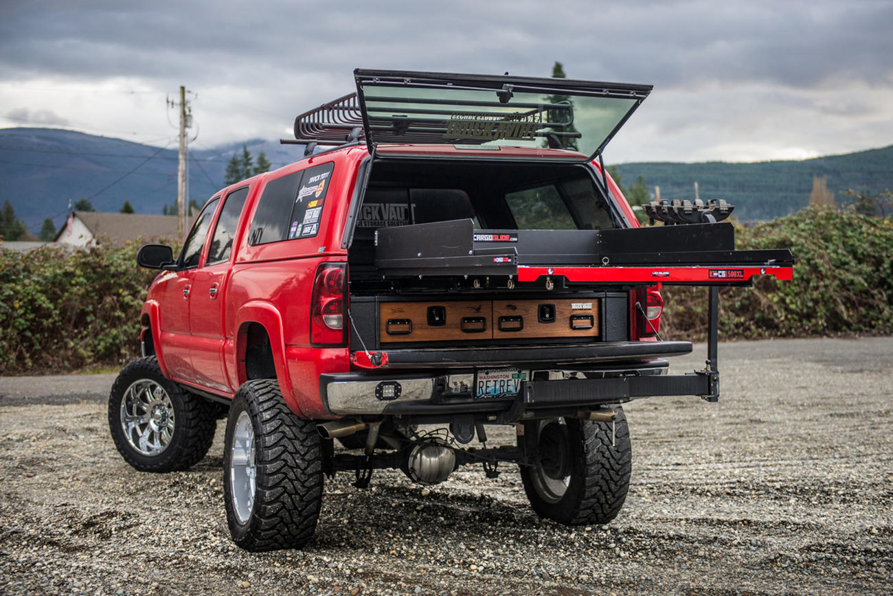 A red Chevy Silverado with a TruckVault and a CargoGlide on top of it.