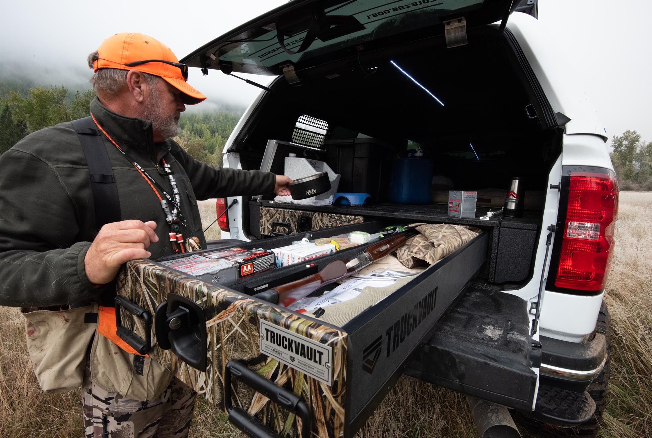 A pheasant hunter opening a TruckVault with a shotgun secured in the drawer.