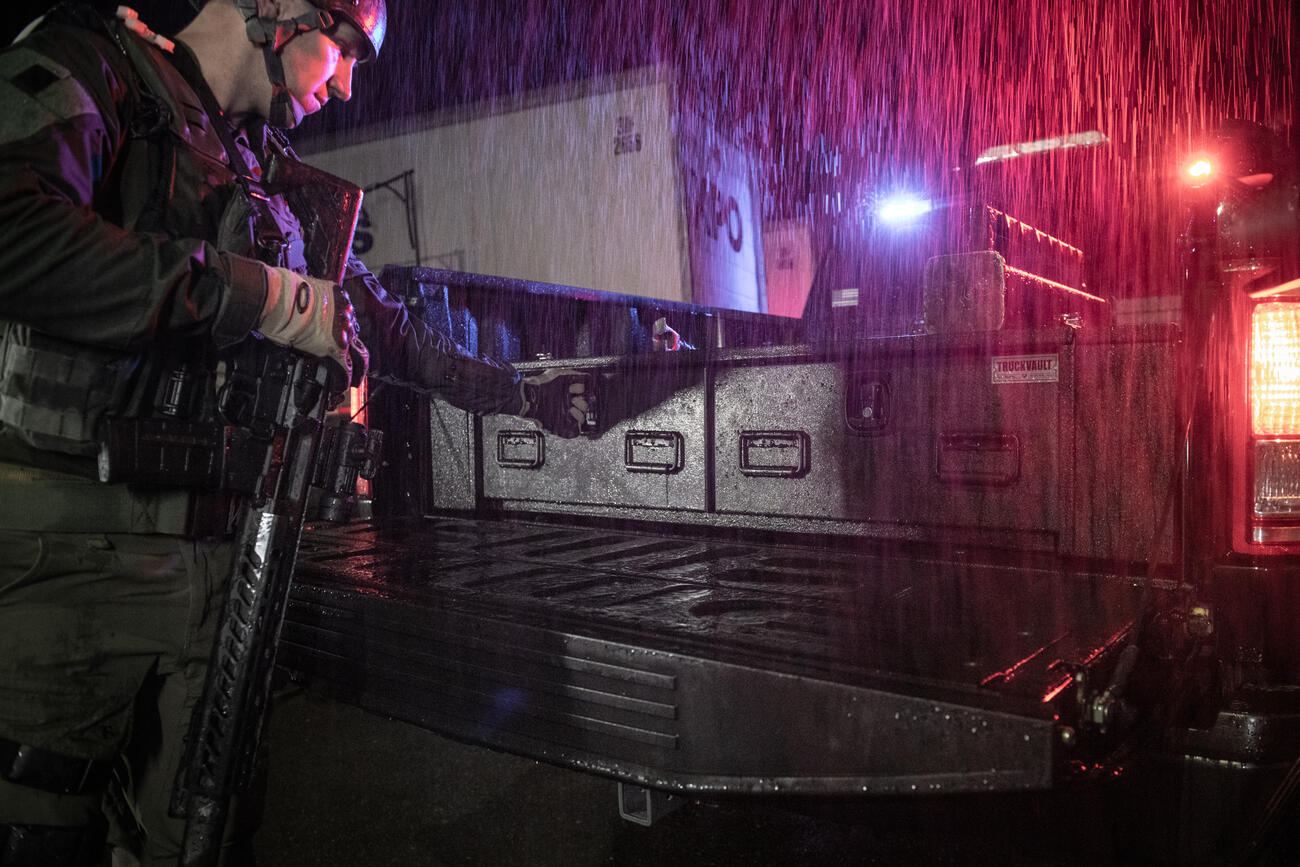 A member of a SWAT team opening an F-150's TruckVault in order to secure his weapon.