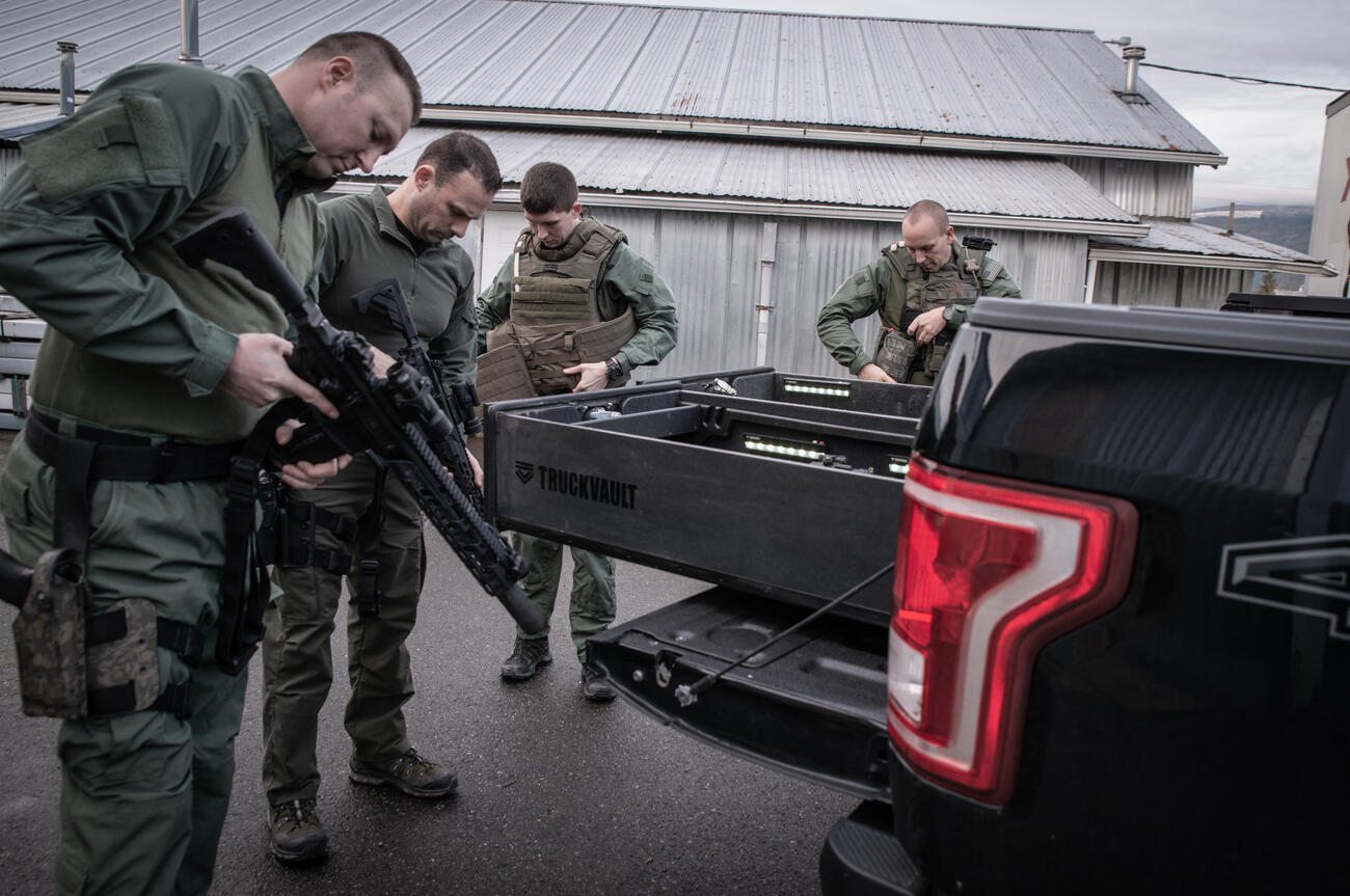 A SWAT team of four checking out their weapons while standing around an all weather TruckVault for a Ford F-150.