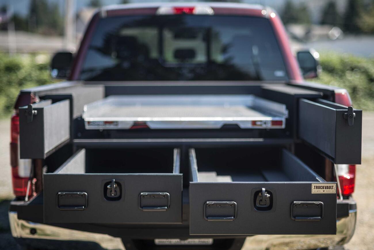 A red Ford F250 with a custom All-Weather TruckVault in the truck bed and a CargoGlide on top.