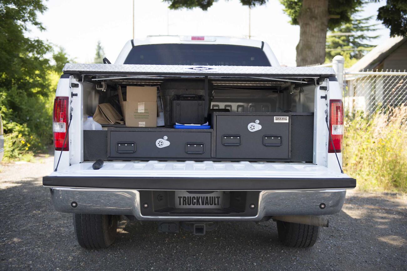 A White Ford F-150 with a covered bed and offset TruckVault drawers.