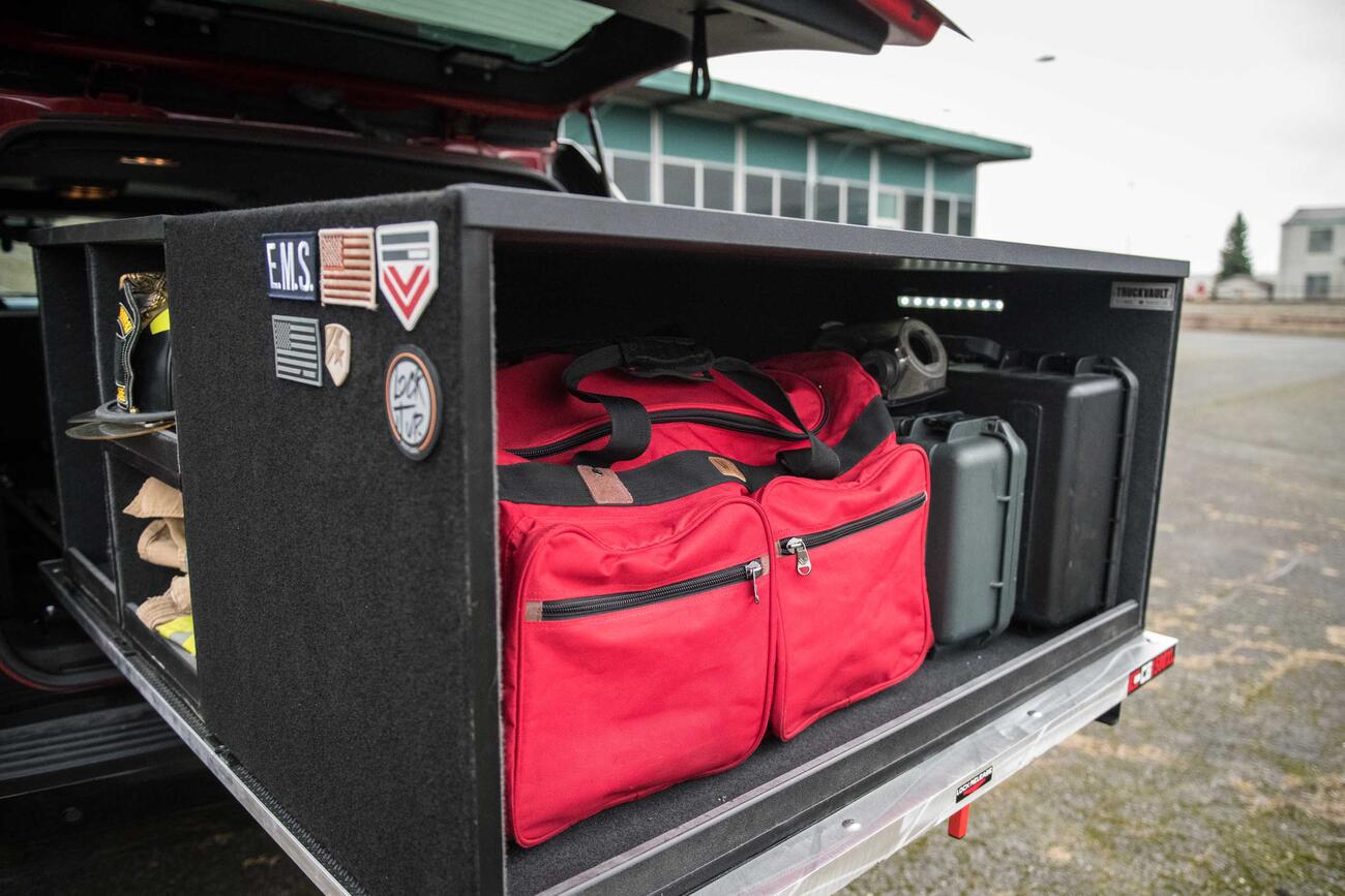 A custom Truckvault in the back of a red Chevy Suburban filled with fire fighting gear.