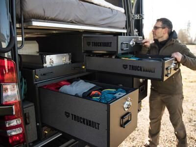 A man rummaging through his TruckVault secure storage system in the back of a Mercedes Sprinter