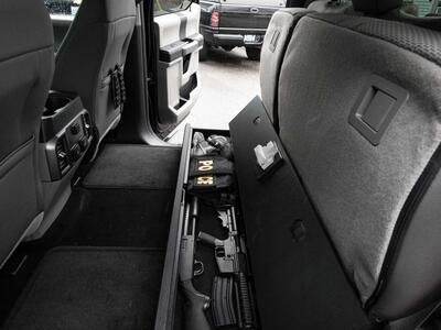 An open SeatVault in the back of a Ford F150 with guns and other police gear.