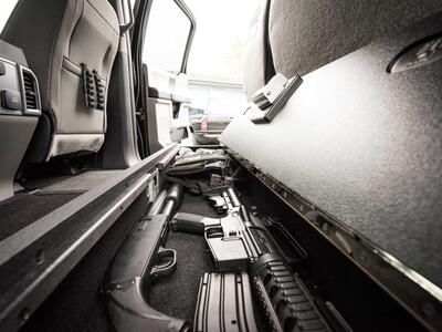 An open SeatVault in the back of a Ford F150 with guns and other police gear.