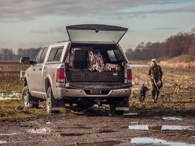 A Ford F-150 with with a Magnum 2 Drawer All-Weather TruckVault storage system in it, sitting in a muddy field.