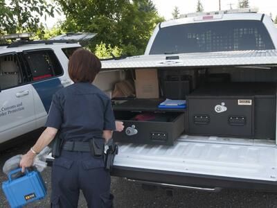 A U.S. Customs and Border Protection officer taking gear out of her White Ford F-150.