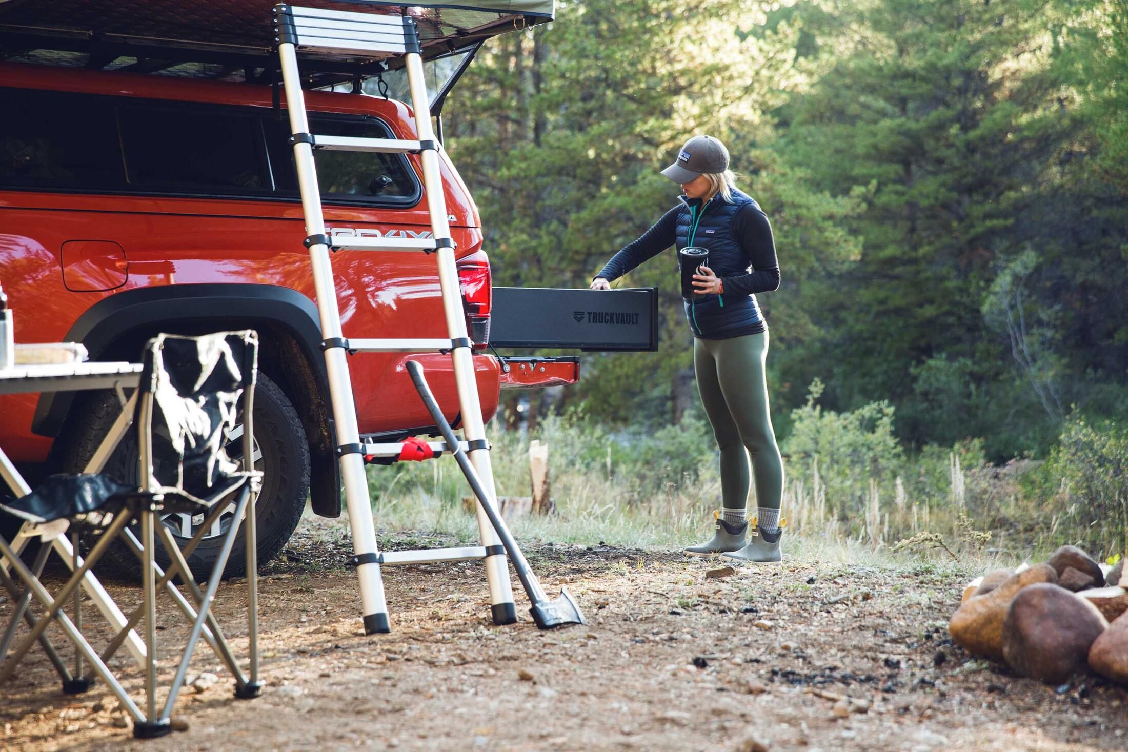 A woman placing gear in a TruckVault. The TruckVault is in the bed of a red truck.