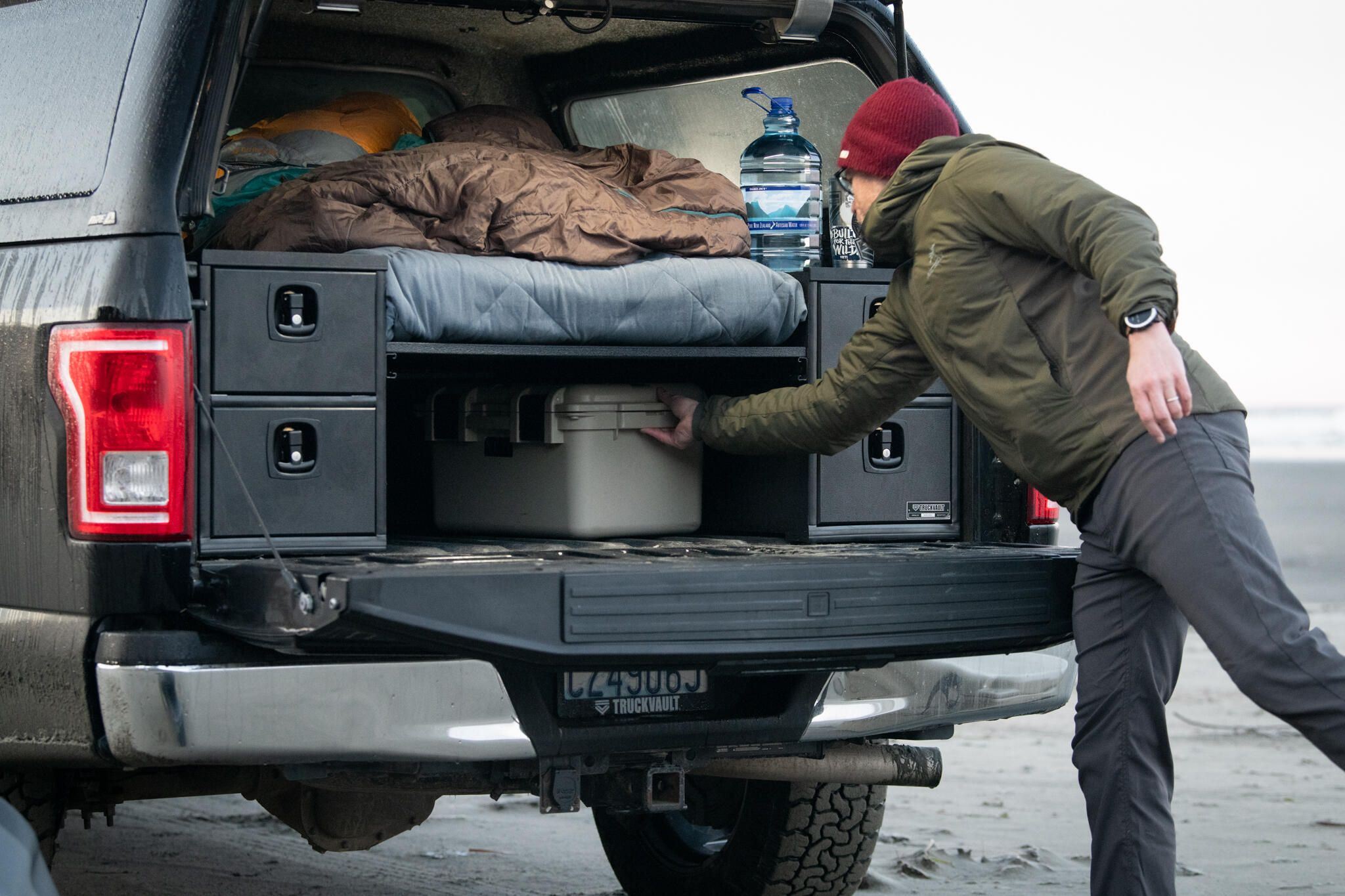 Man pulls box from storage underneath sleeping platform in TruckVault Base Camp 4