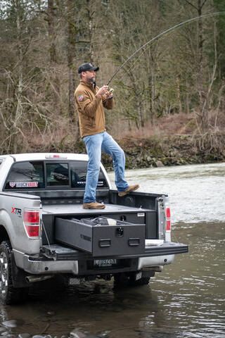 All Weather 2-drawer TruckVault in back of Ford f-150 with fly-fisherman standing on top of unit. 1 drawer open.
