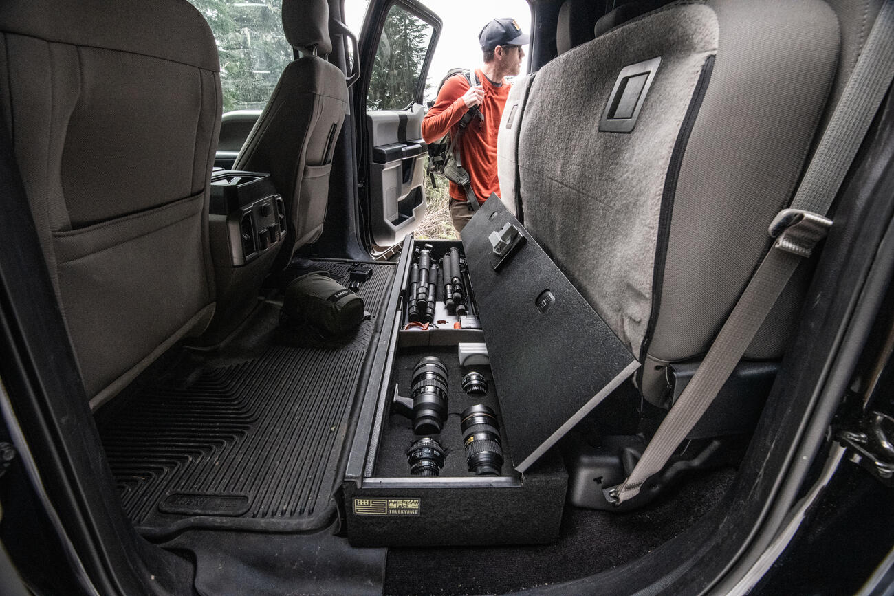 photographer chooses camera gear from SeatVault storage system under seat in pickup truck