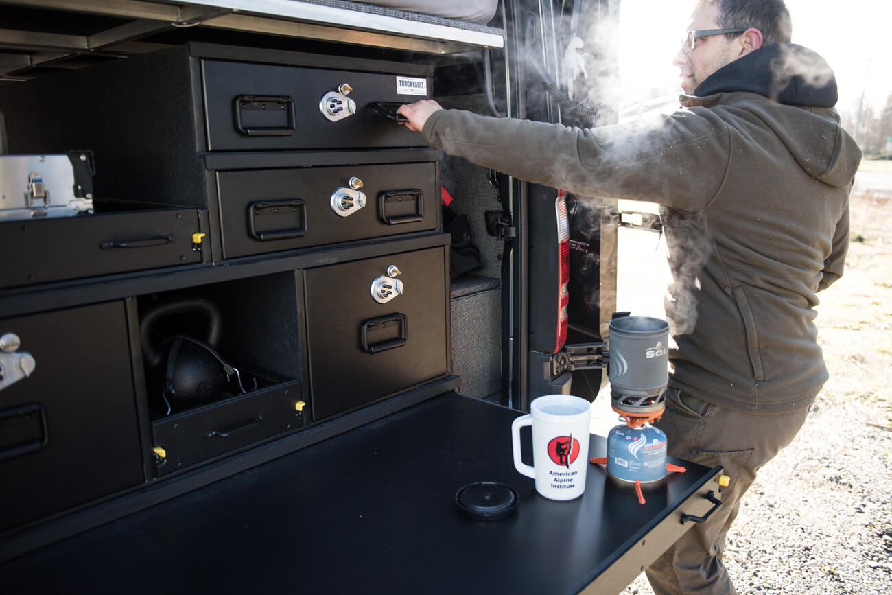 Man opening overlanding camping vehicle organization using TruckVault secure storage system in Mercedes Sprinter van