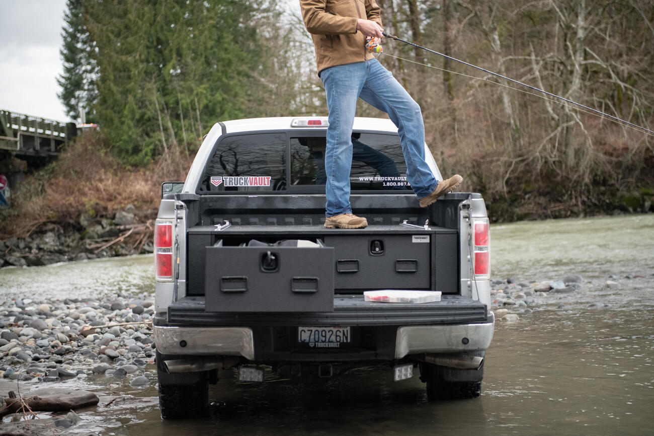 fly fishing fisherman standing on top of magnum TruckVault secure truck bed drawer system in pickup truck Ford F-150