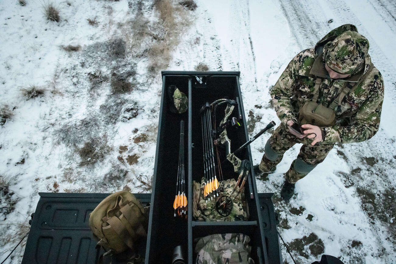 snowy day as outdoorsman reaches into extended drawers of half width TruckVault secure storage system for pickup truck