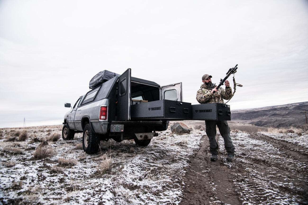 tactical trainer setting up rifle from the back of his covered pickup truck with drawers of TruckVault secure storage for pickup trucks extended