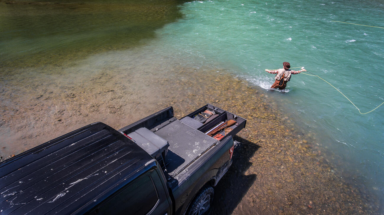 Man fly fishing in the confluence of two rivers with his TruckVault.