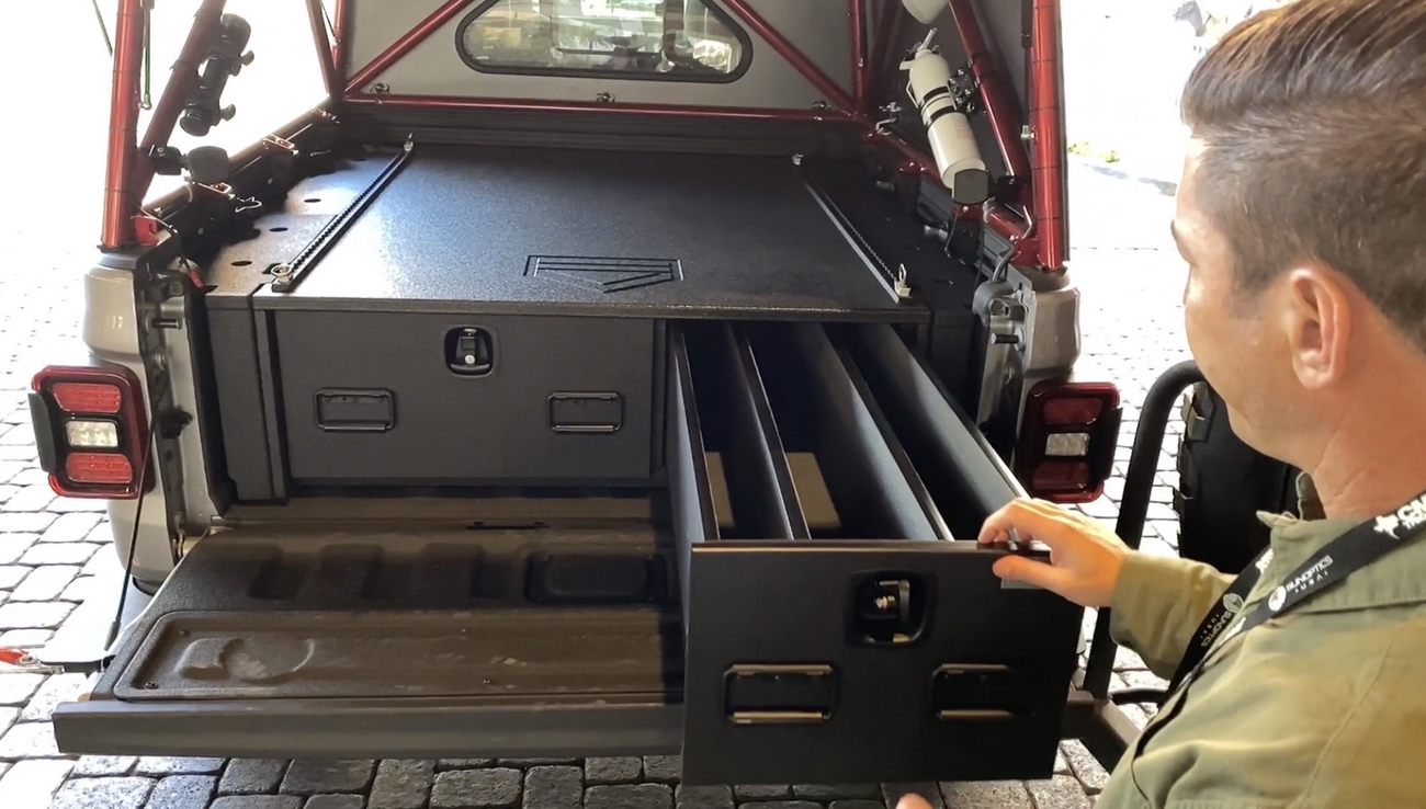 A man pulling out the drawer from a TruckVault storage system installed in the back of a Jeep Gladiator.