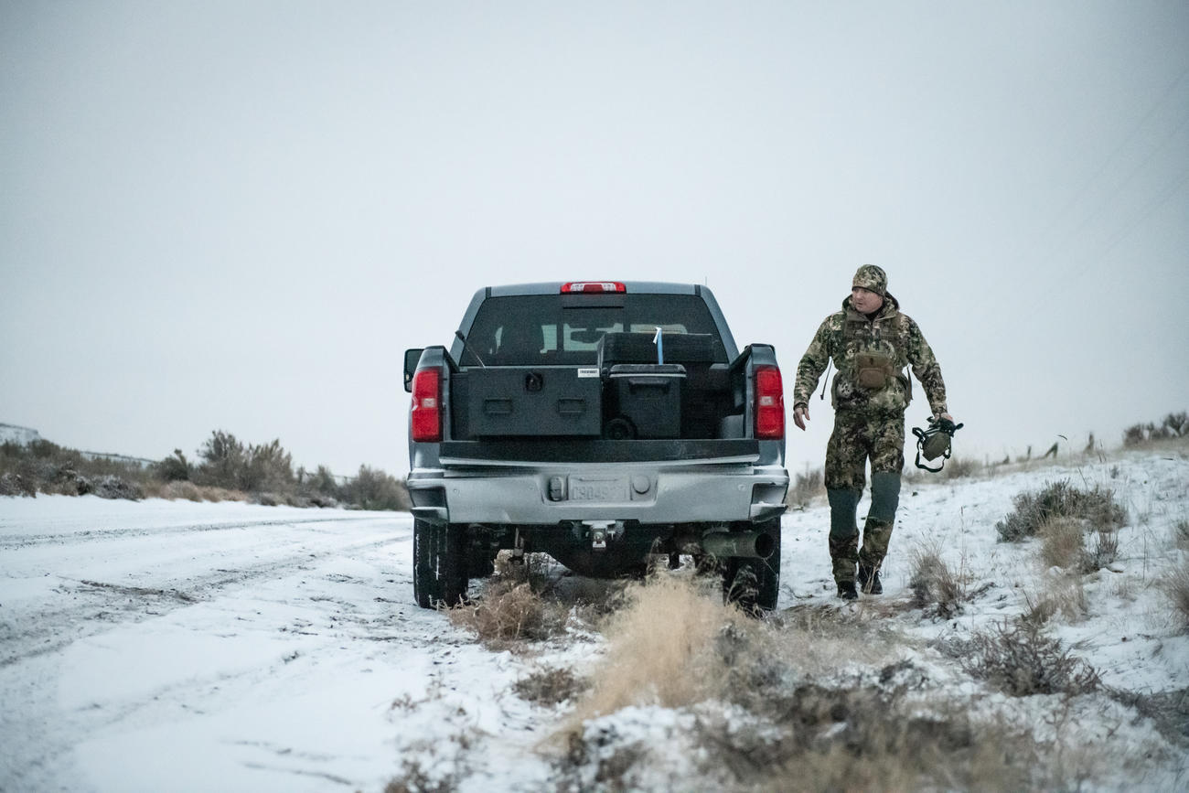 snowy day as hunter walks to back of Chevy Silverado where an All Weather Half Width TruckVault secure truck bed storage system is shown in the truck bed