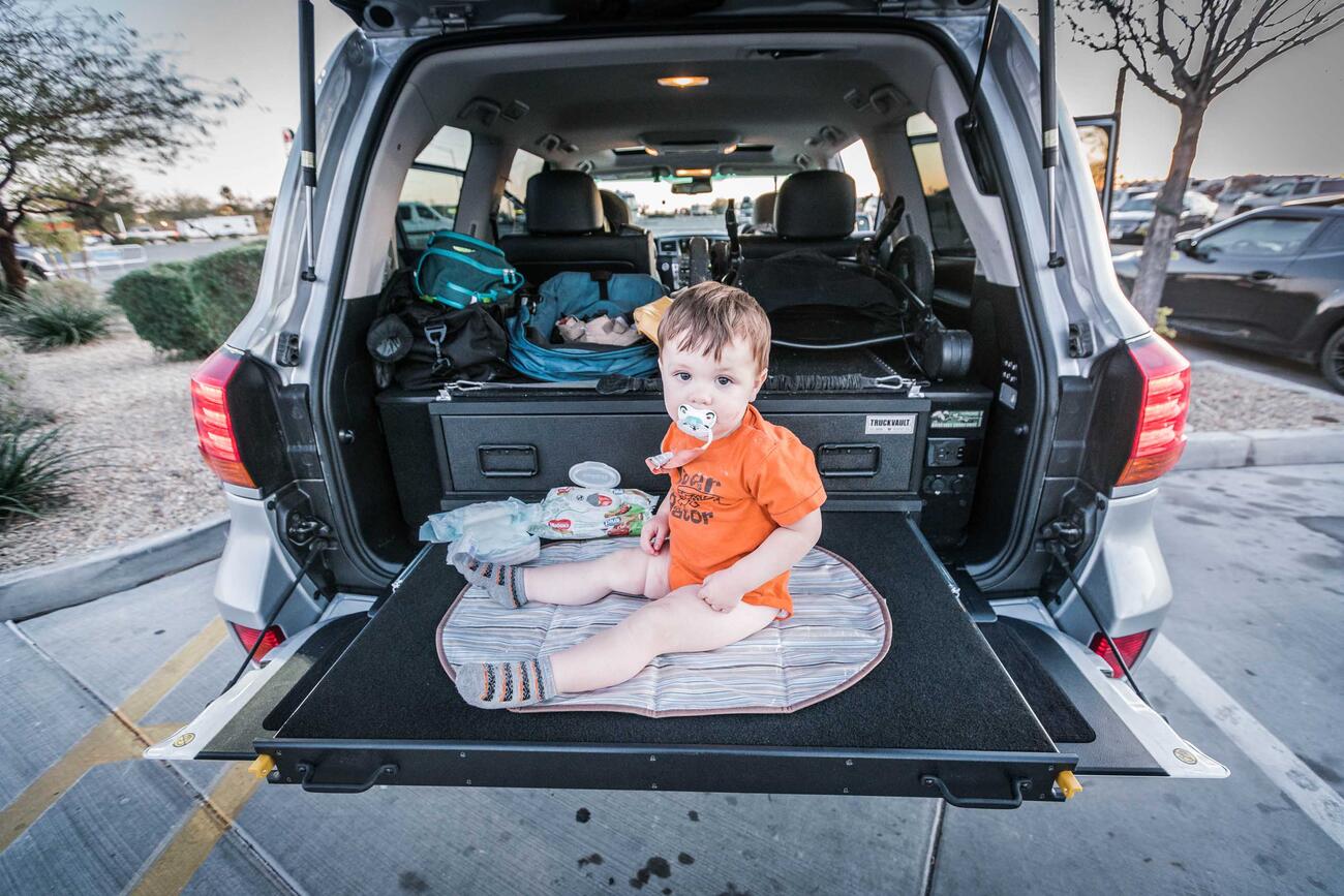 A baby sitting on a heavy duty pull out table in a Lexus LX570.