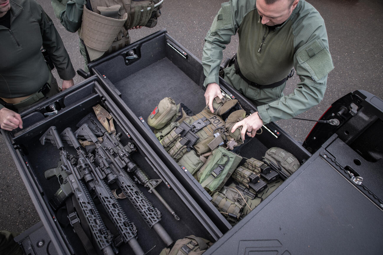 A SWAT team grabbing a bulletproof vest and assault rifles out of TruckVault inside of a Black F-150.