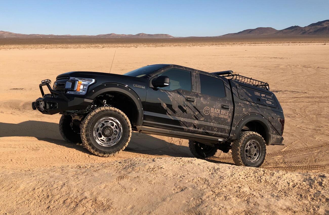 the Black Rifle Coffee Company truck driving up a sand dune in the desert.