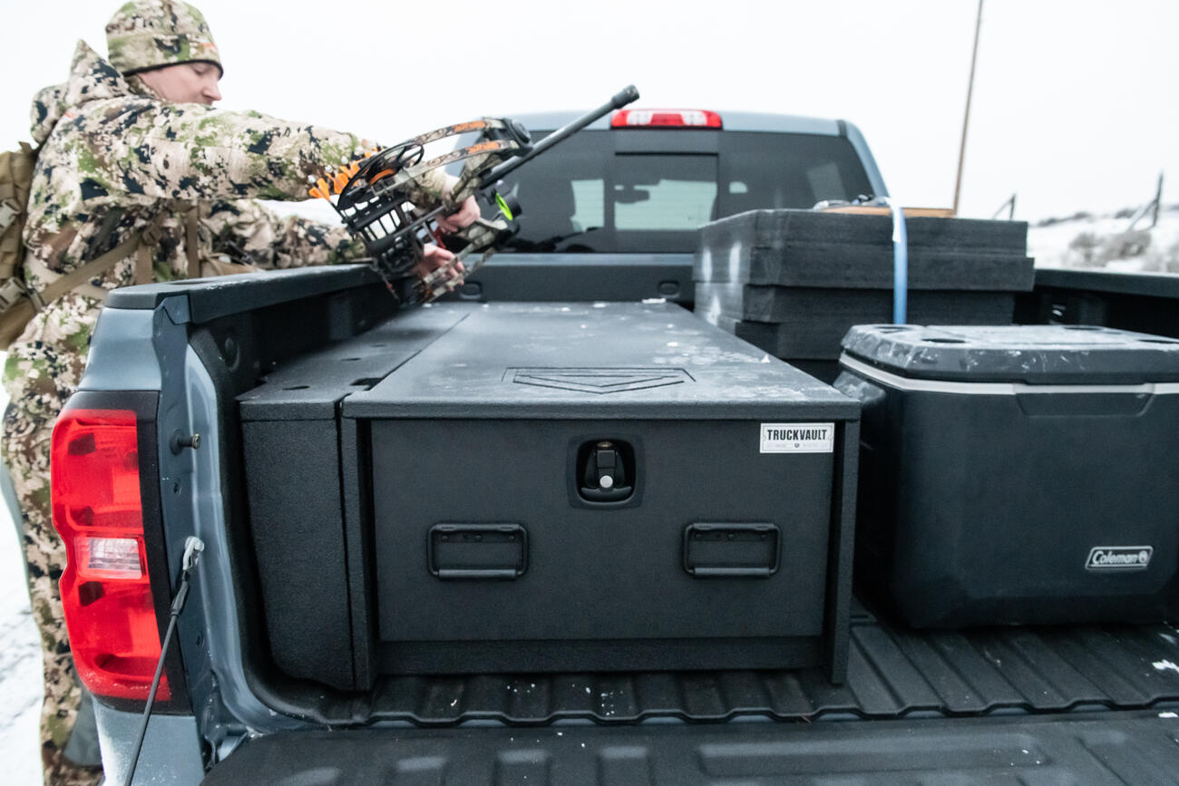 A man in camouflage placing his bow on top of a Half Width TruckVault.