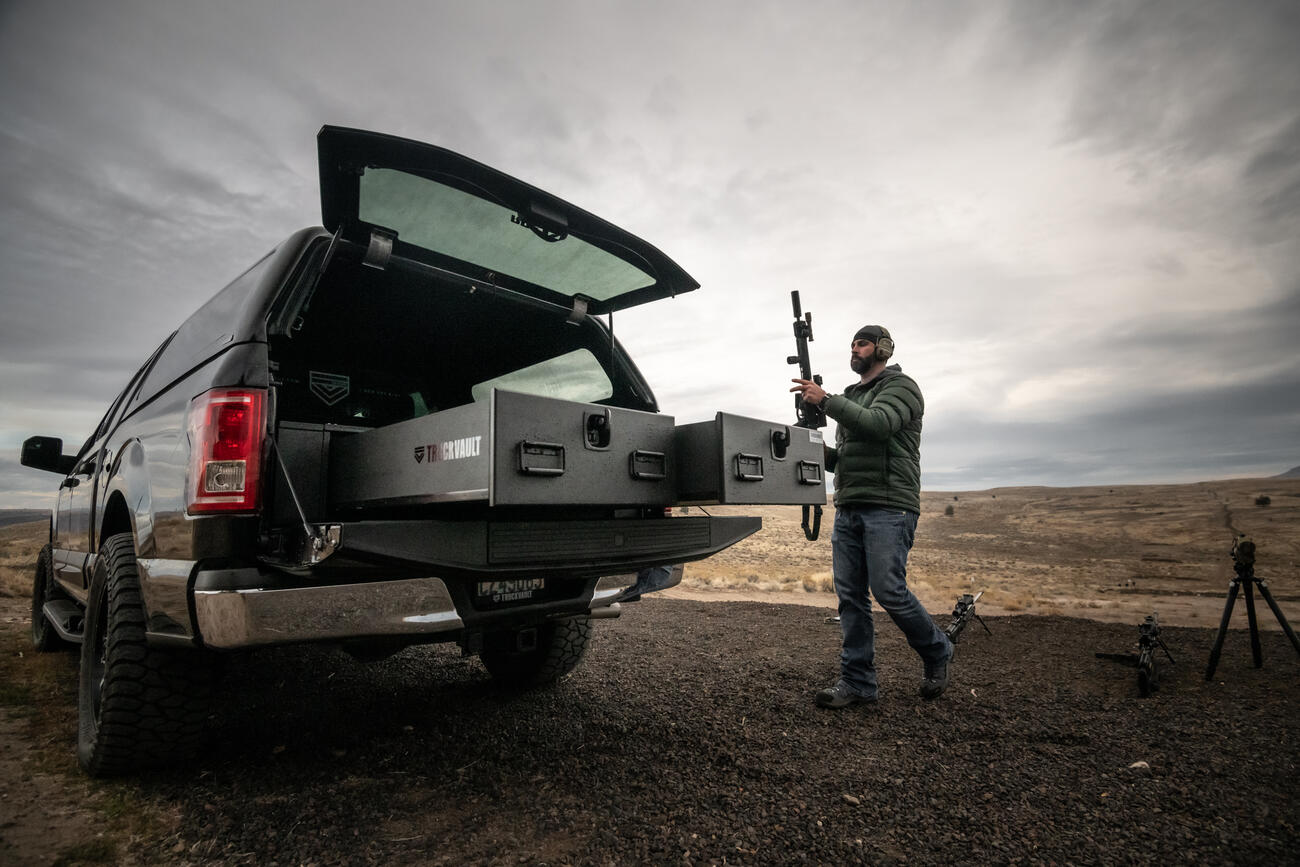 A man grabbing his assault rifle out of the back of his TruckVault in a Ford F-150.