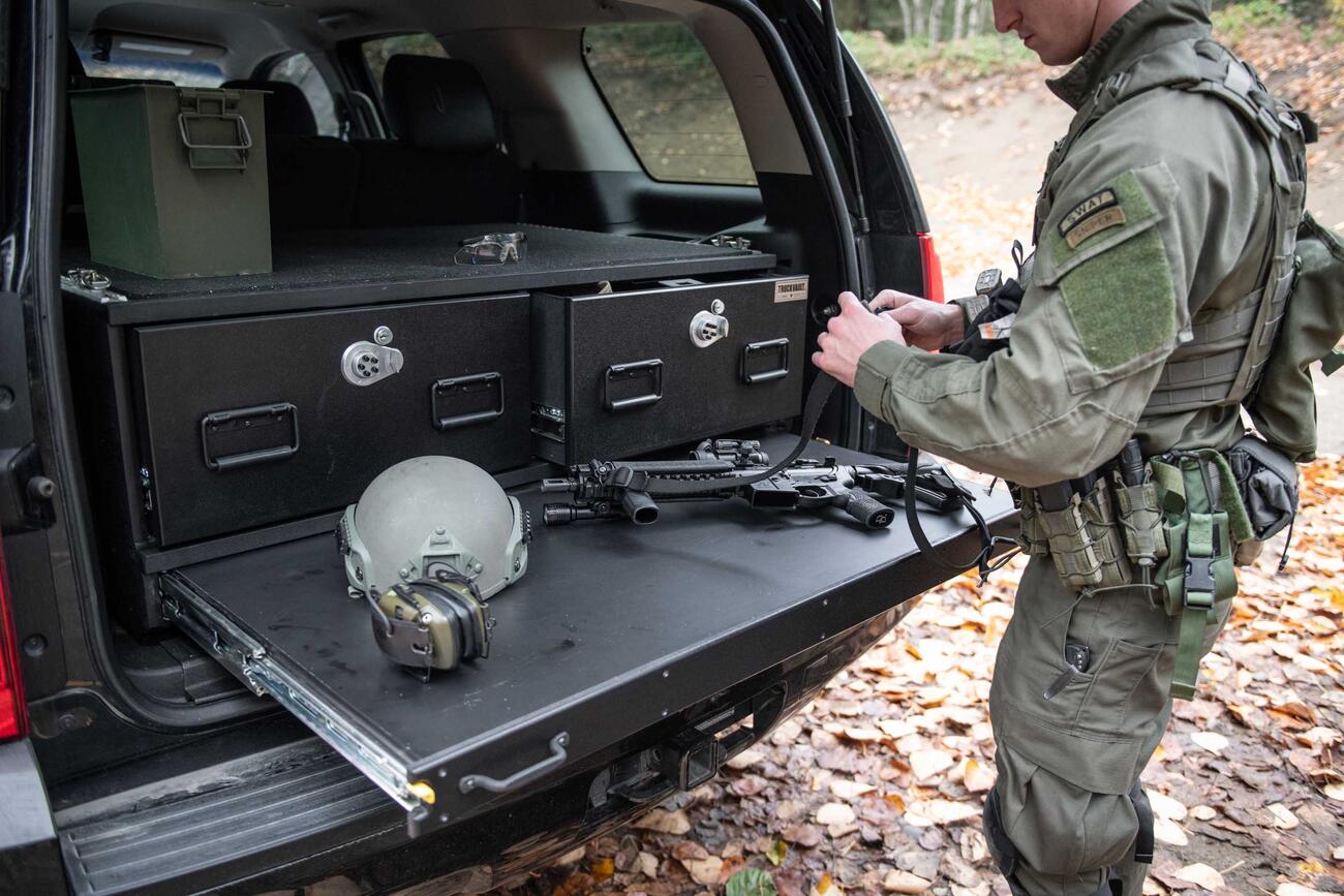 A SWAT officer working on his gun on a heavy duty pull out table on a TruckVault in the back of Chevy Tahoe.