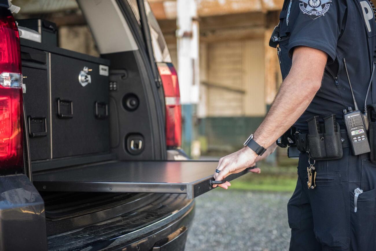 A police officer opening a pull-out table in a Chevy Suburban.