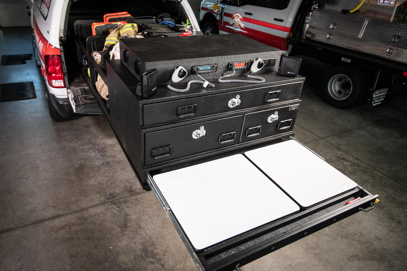 Pro Line 6 Sliding Command Center extends from pickup truck showcasing secure storage, heavy duty work surface, dry erase boards, and radio panel with inverter