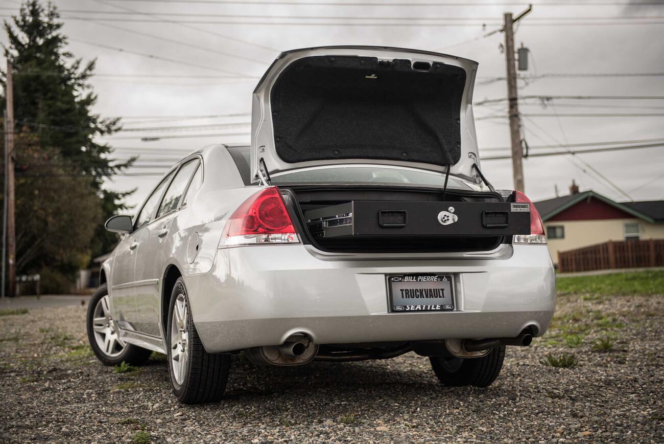 A Chevy Impala with an open, elevated TruckVault in the cargo area.