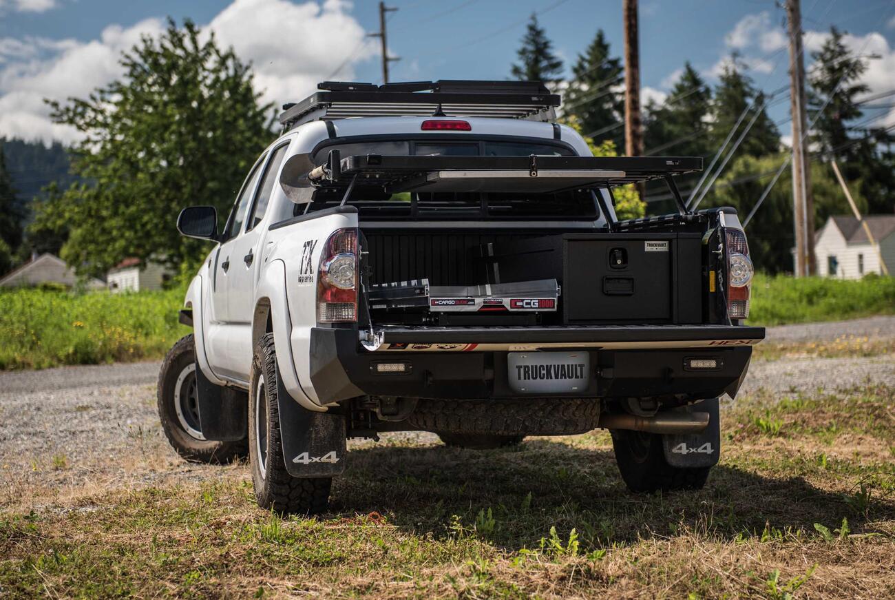 A white truck with a TruckVault and a cargo slide in the bed.