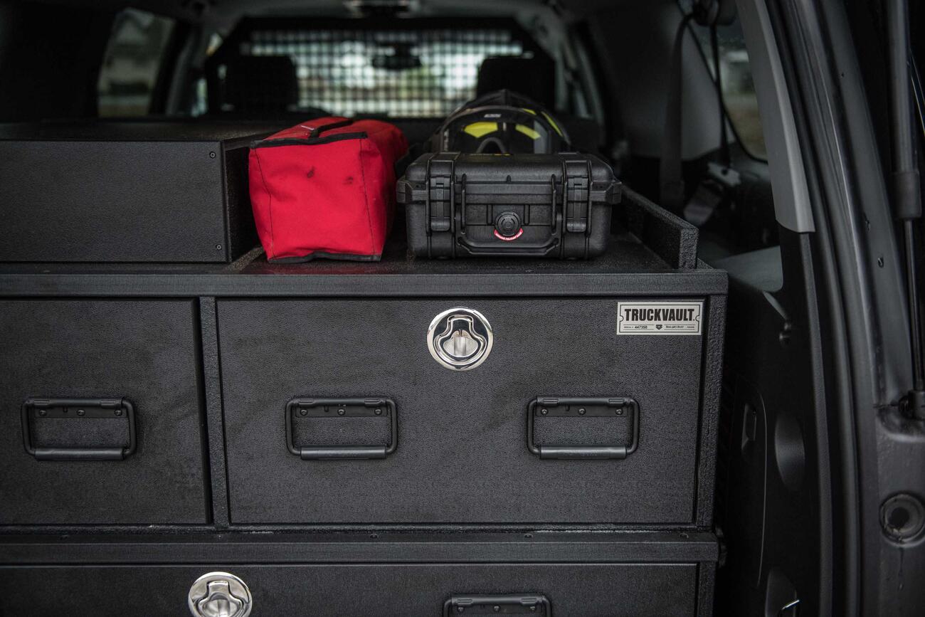 A custom TruckVault with boxes on top. All inside of a red Chevy Suburban.