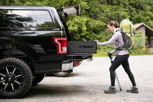 A woman closing her TruckVault storage system while heading out for a hike.