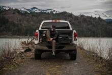 A man sitting on the tailgate of his Ford F-150 getting ready to go hunt.