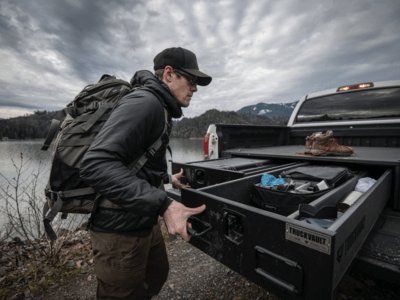 outdoorsman selecting hiking gear from drawer of TruckVault secure truck bed storage system for pickup truck