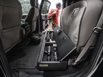 photographer chooses camera gear from SeatVault storage system under seat in pickup truck
