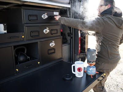 Man opening overlanding camping vehicle organization using TruckVault secure storage system in Mercedes Sprinter van