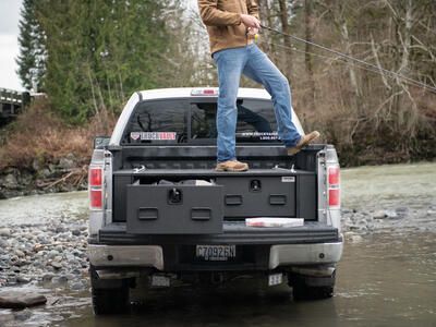 fly fishing fisherman standing on top of magnum TruckVault secure truck bed drawer system in pickup truck Ford F-150