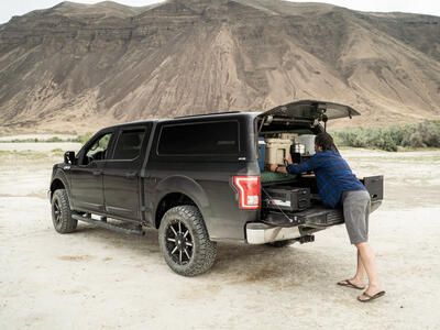 man packing TruckVault secure truck bed storage system in black pickup truck with covered truck bed