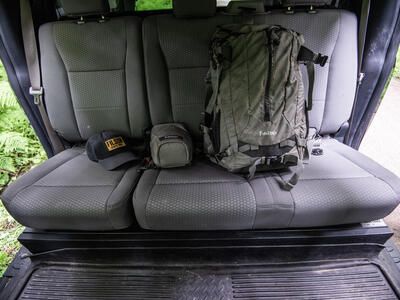 grey SeatVault hidden underneath back seat bench seat of pickup truck with backpack and ball cap on seat