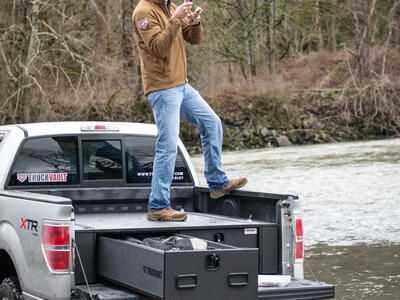 fly fishing fisherman standing on top of magnum TruckVault secure truck bed drawer system in pickup truck Ford F-150 one drawer open