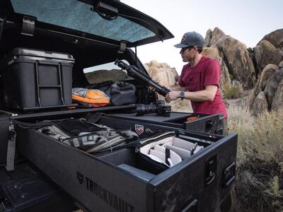 photographer pulls camera gear form truck bed drawers of TruckVault secure storage system in covered pickup truck bed