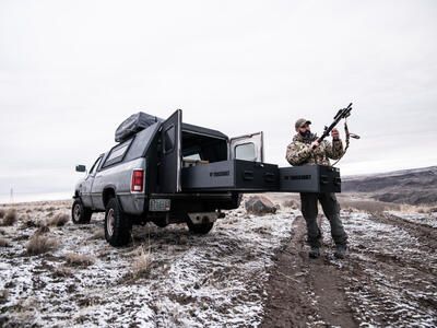 tactical trainer setting up rifle from the back of his covered pickup truck with drawers of TruckVault secure storage for pickup trucks extended