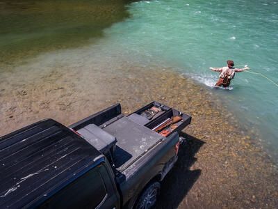 Man fly fishing in the confluence of two rivers with his TruckVault.