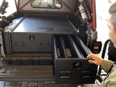 A man pulling out the drawer from a TruckVault storage system installed in the back of a Jeep Gladiator.