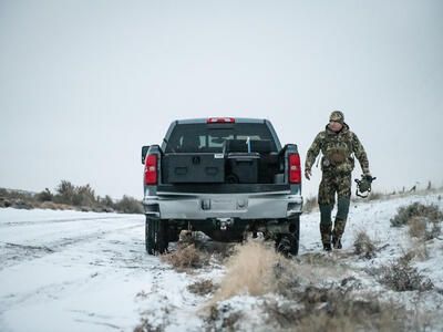 snowy day as hunter walks to back of Chevy Silverado where an All Weather Half Width TruckVault secure truck bed storage system is shown in the truck bed