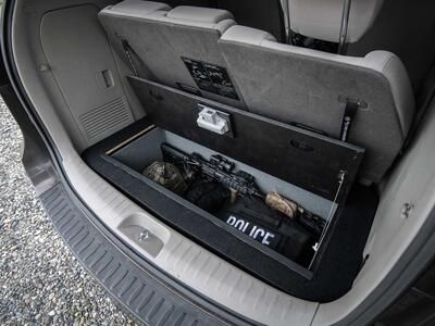 An open Kia Sedona FloorVault filled with a gun and police gear.