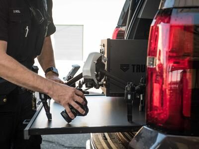 A police officer working on his drone on a pull-out table attached to his black Chevy Suburban.